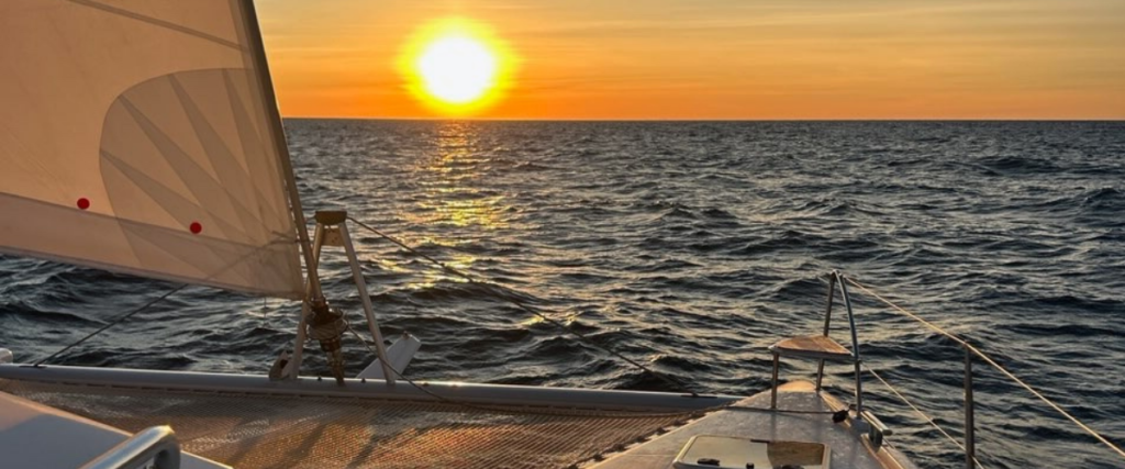 Vue depuis un catamaran en mer au coucher du soleil, symbole d’un projet de vie en mer préparé et réfléchi