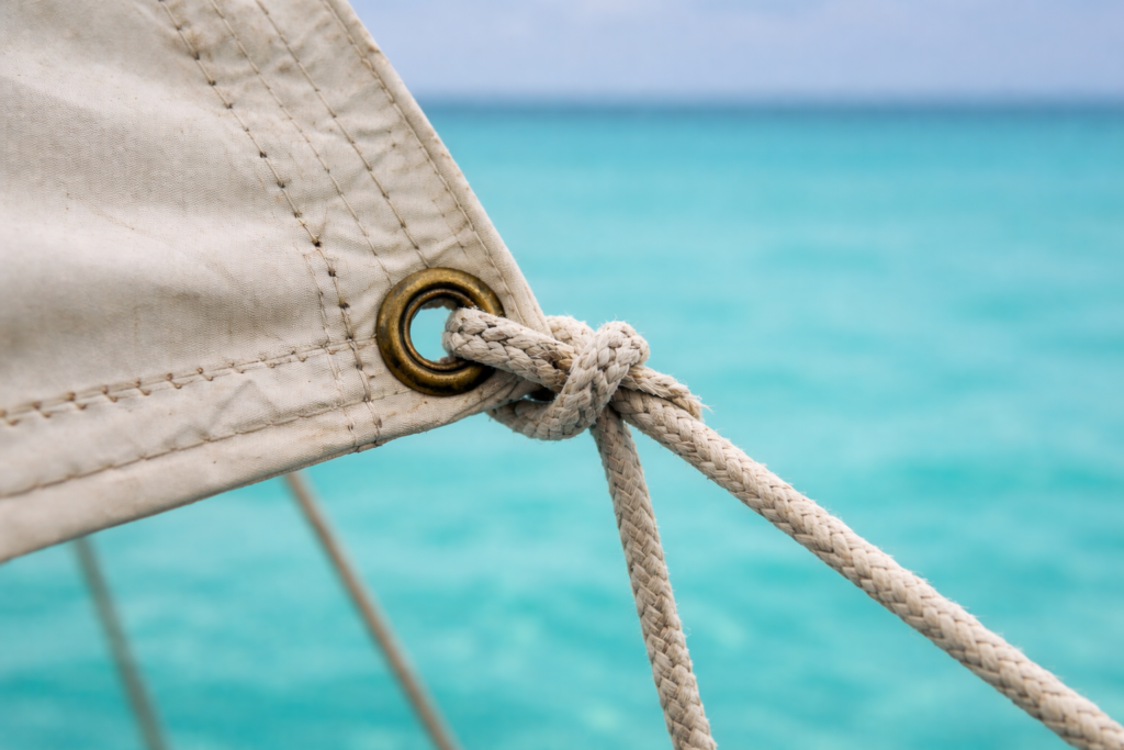 Corde de voile attachée dans un œillet métallique sur une voile avec la mer en arrière-plan