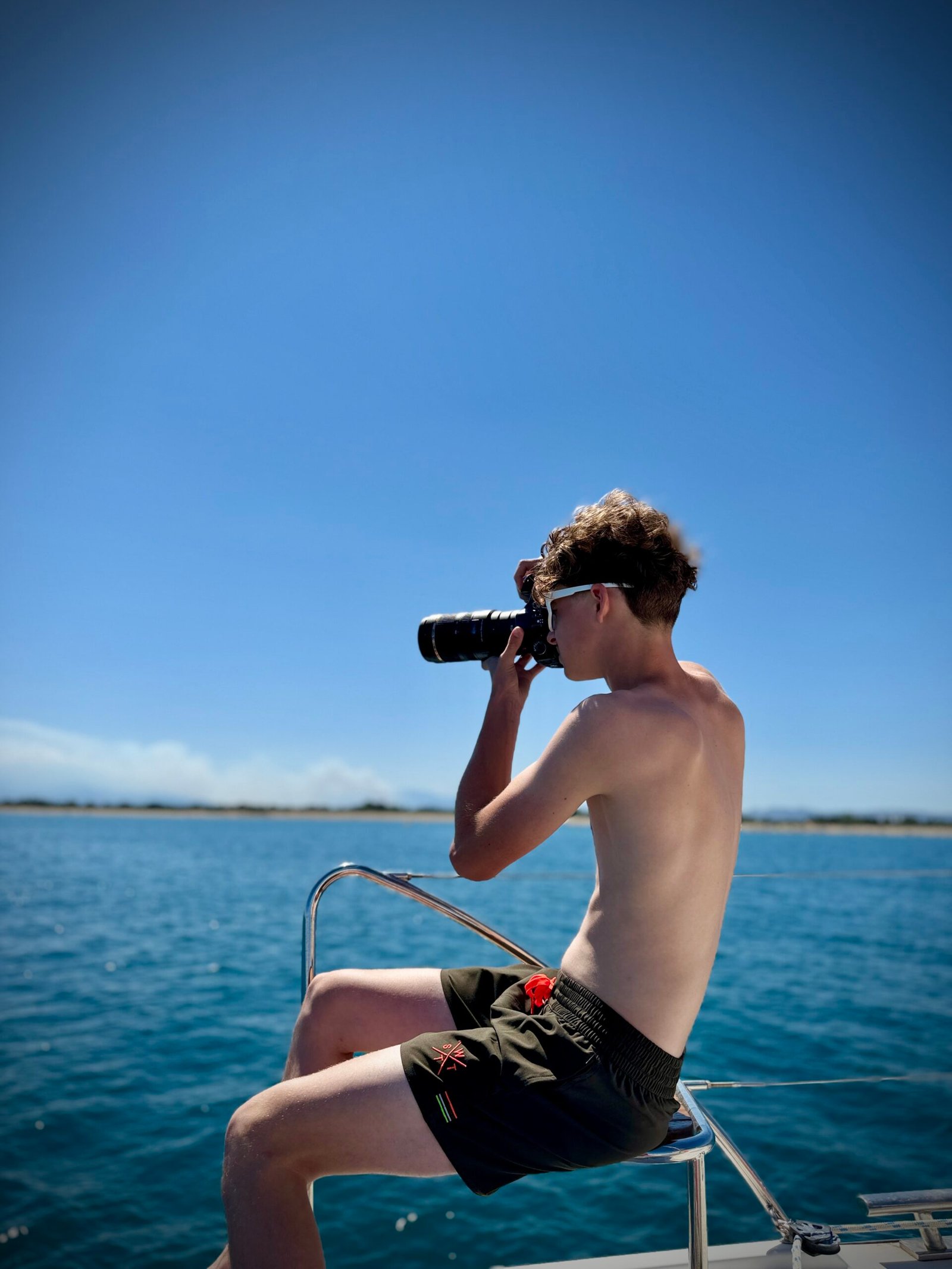 Jeune photographe prenant une photo depuis un bateau en mer